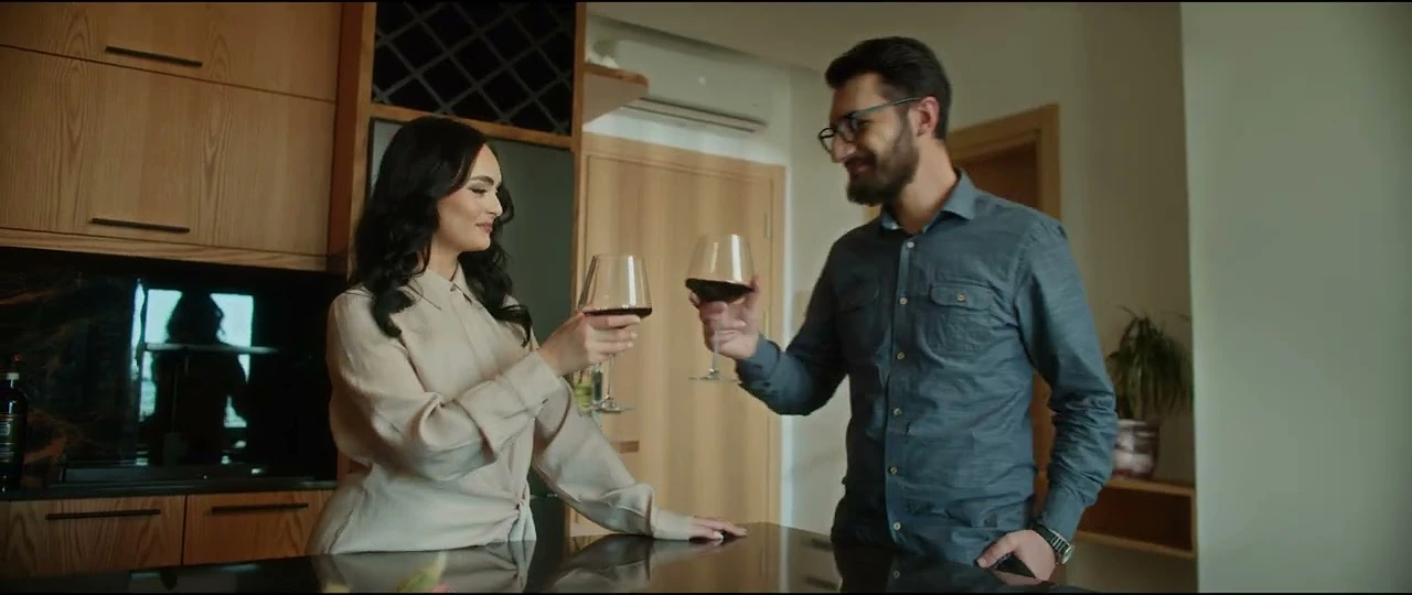 A couple raising glasses in a warmly lit kitchen