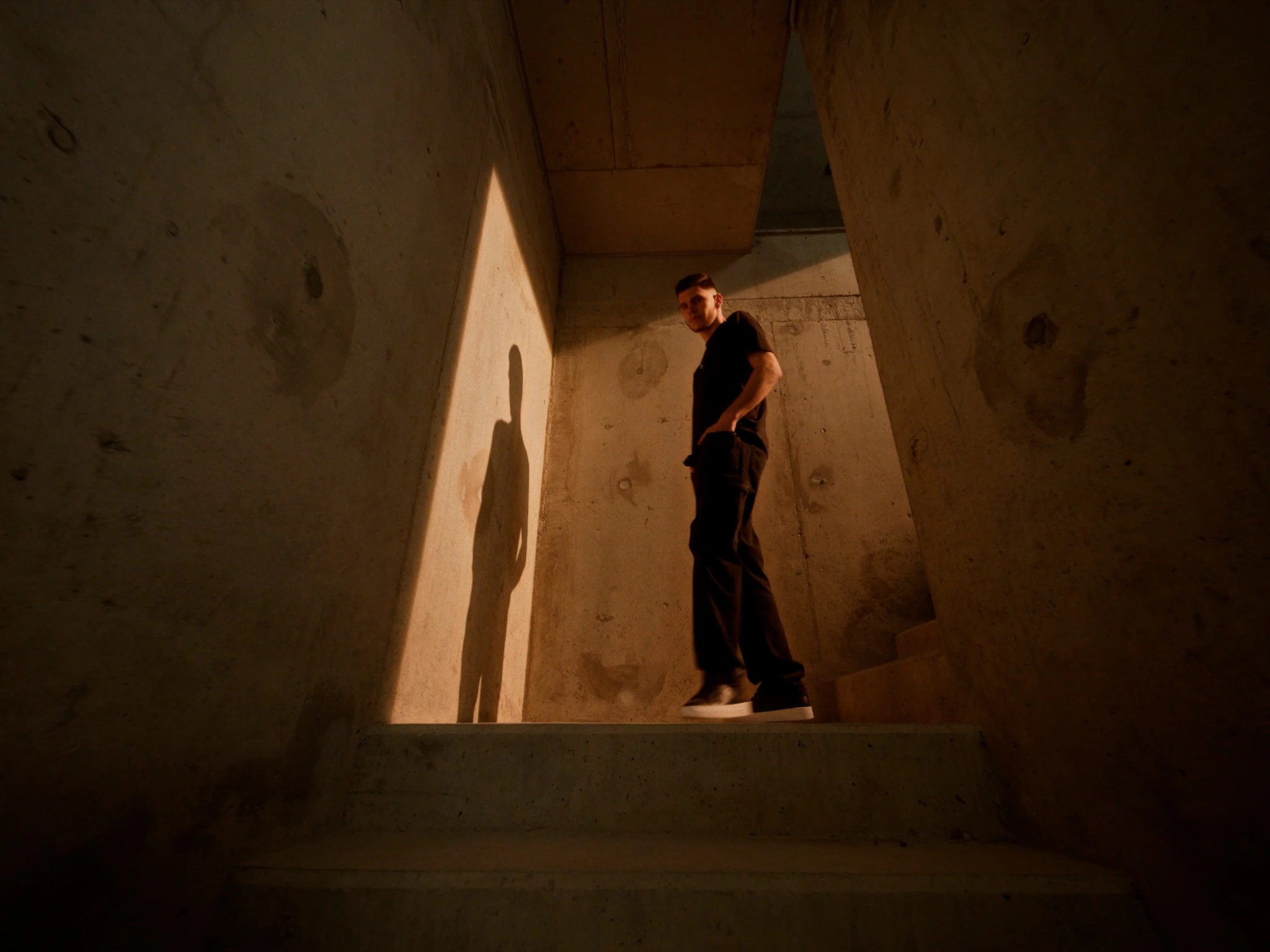 A young man standing on concrete stairs in warm light in HSW