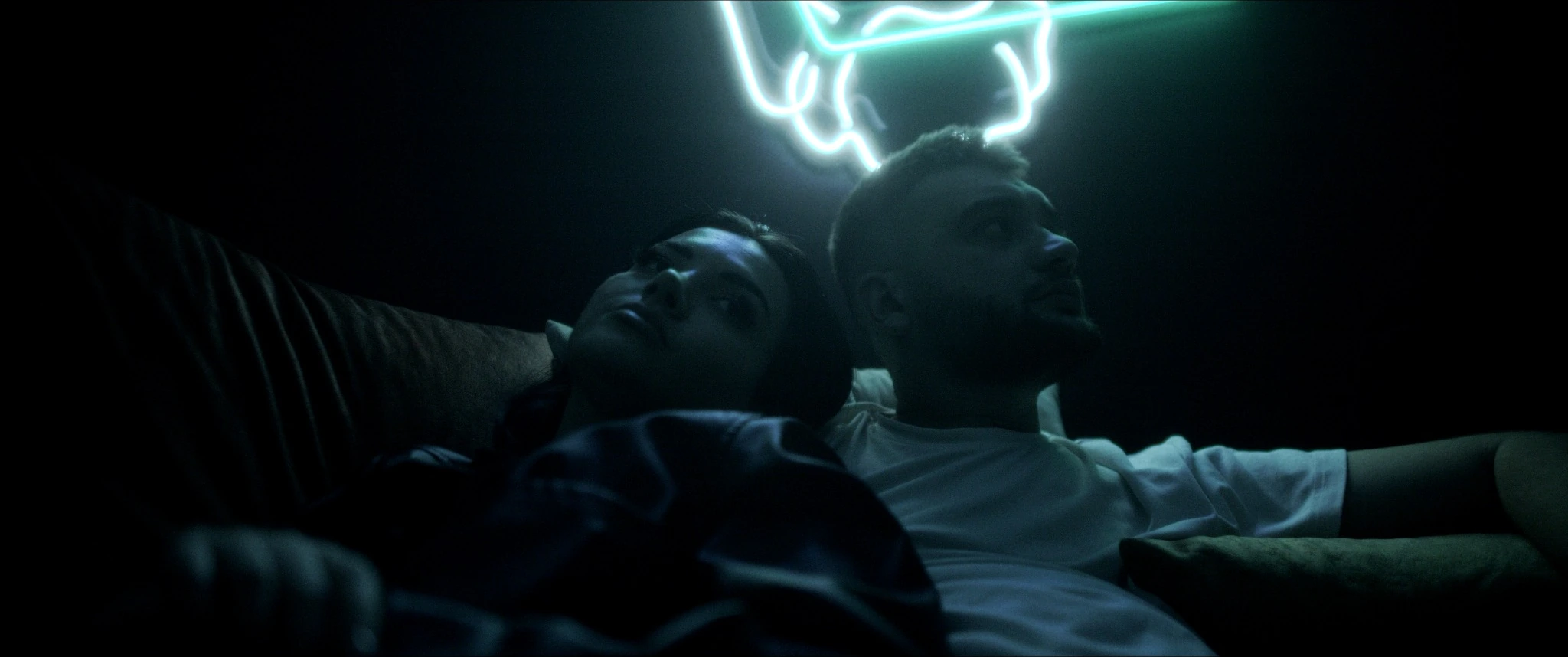 A young couple with a glowing neon sign behind them in FSSIUF