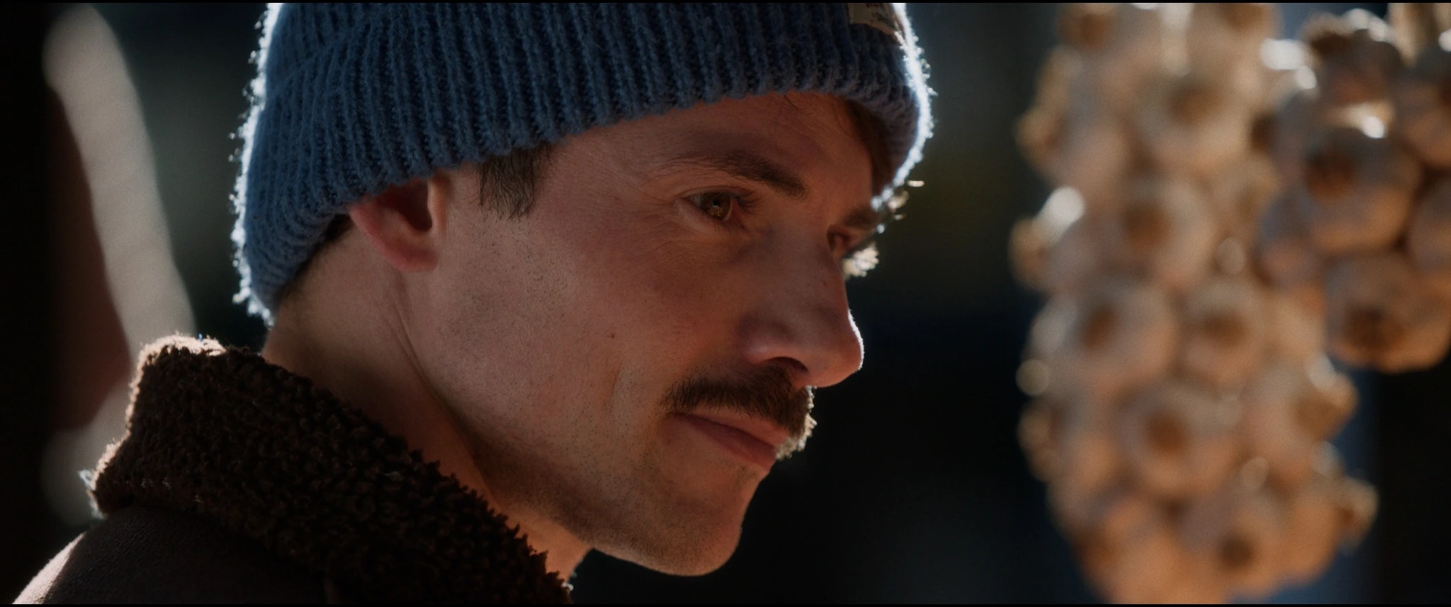 Side profile of a man in a blue knit hat at a market in Collateral Damage